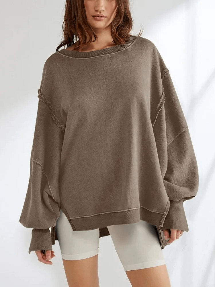 Woman wearing an oversized sweatshirt with reversible seam, full sleeves, O-neck, and patchwork detail, paired with white shorts.